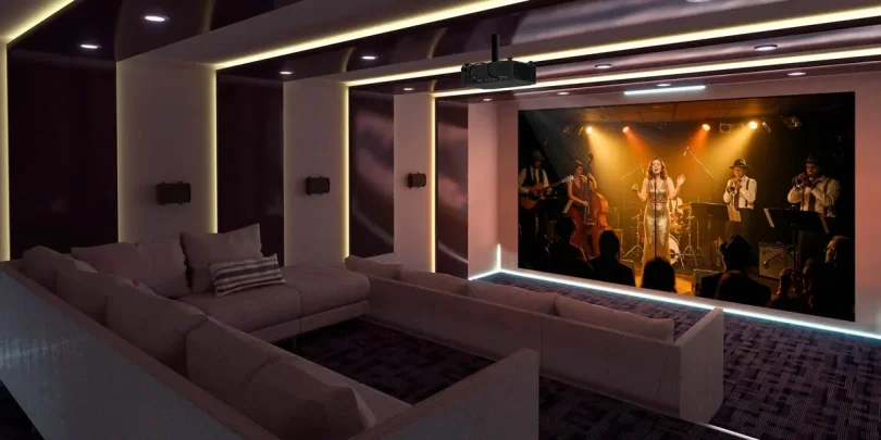 Projecteur Optoma UHZ78LV installé au plafond dans une salle de home cinéma luxueuse, projetant un concert avec des couleurs vives grâce à la technologie laser triple RGB.