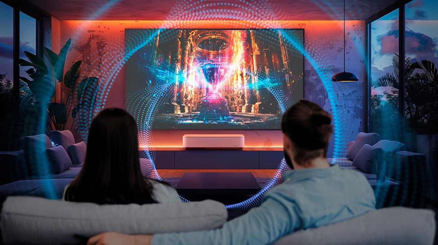 Couple installé dans un canapé regardant un film sur grand écran projeté par le Epson EH-LS970W finition blanche posé sur meuble TV avec visualisation des ondes sonores spatiales bleues et rouges illustrant l'immersion audio Bose Dolby Audio dans un salon home cinéma ambiance LED