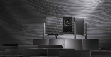 Projecteur 4K XGIMI TITAN Noir Max à triple laser RGB et double iris, badge IMAX Enhanced et grille audio Harman Kardon, posé sur un socle métallique dans un décor sombre à stries lumineuses.