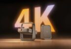 Projecteur portable XGIMI Z9X 4K High Brightness Edition au design cadre-poignée cardan, finition bronze, posé à côté de son bloc d'alimentation devant un mur LED géant affichant 4K en lettres lumineuses orange et blanches
