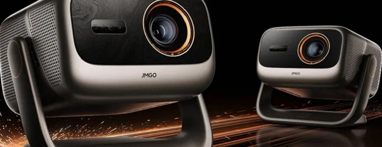 Deux vidéoprojecteurs JMGO Iris triple laser 4K 120 Hz, coque argent champagne, façade noire, objectif cerclé d'orange et rotule en U, sur fond noir avec étincelles cuivrées