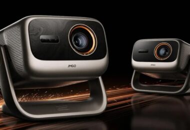 Deux vidéoprojecteurs JMGO Iris triple laser 4K 120 Hz, coque argent champagne, façade noire, objectif cerclé d'orange et rotule en U, sur fond noir avec étincelles cuivrées