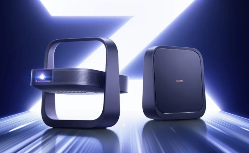 Deux projecteurs portables XGIMI Z6X Pro 2026 bleu nuit, l'un vu de face objectif laser allumé dans son support carré intégré, l'autre de dos avec logo XGIMI, sur fond lumineux bleu